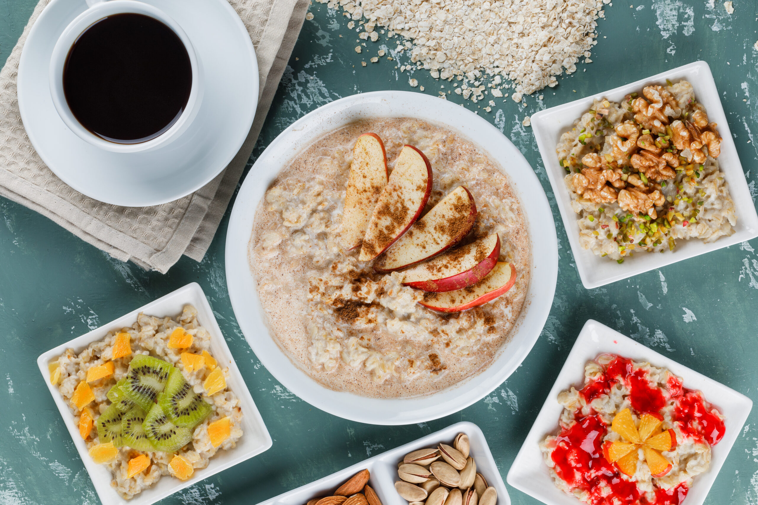 Mingau de aveia 1 Oatmeal in plates with fruits, jam, nuts, cinnamon, coffee, oat flakes flat lay on a plaster background