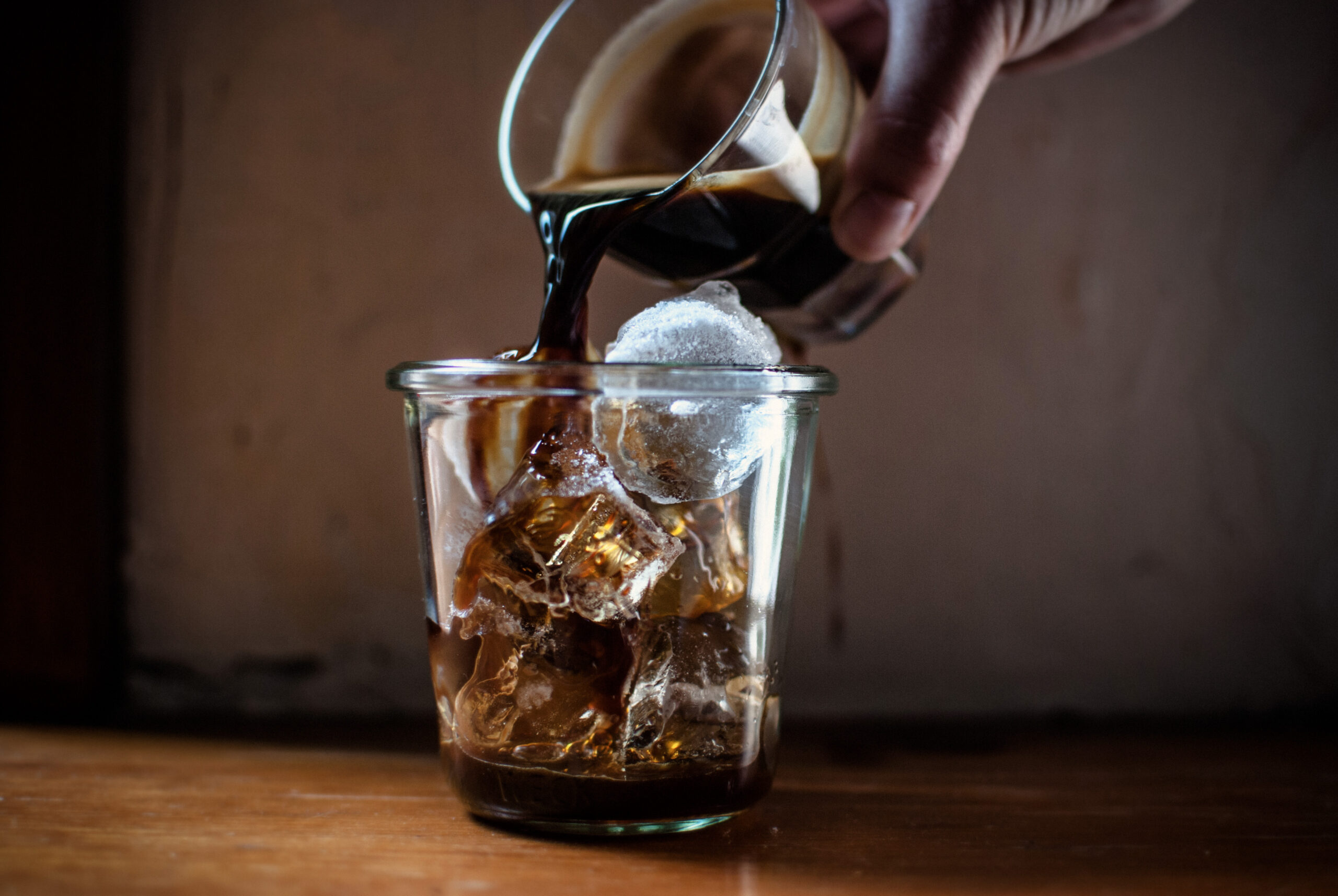 person-pouring-hot-coffee-glass-with-ice