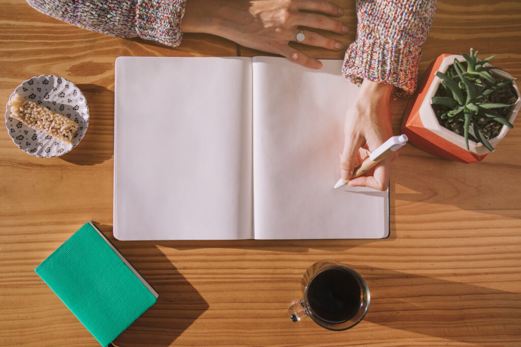 woman writing pen with blank white notebook wooden desk