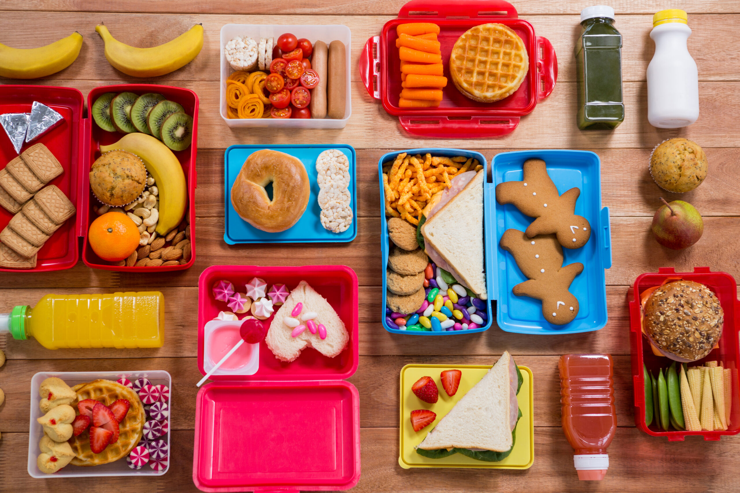 4 lanches rápidos e deliciosos que as crianças vão amar — veja como fazer! 1 Lunch box with various snack, fruit and sweet food on wooden table