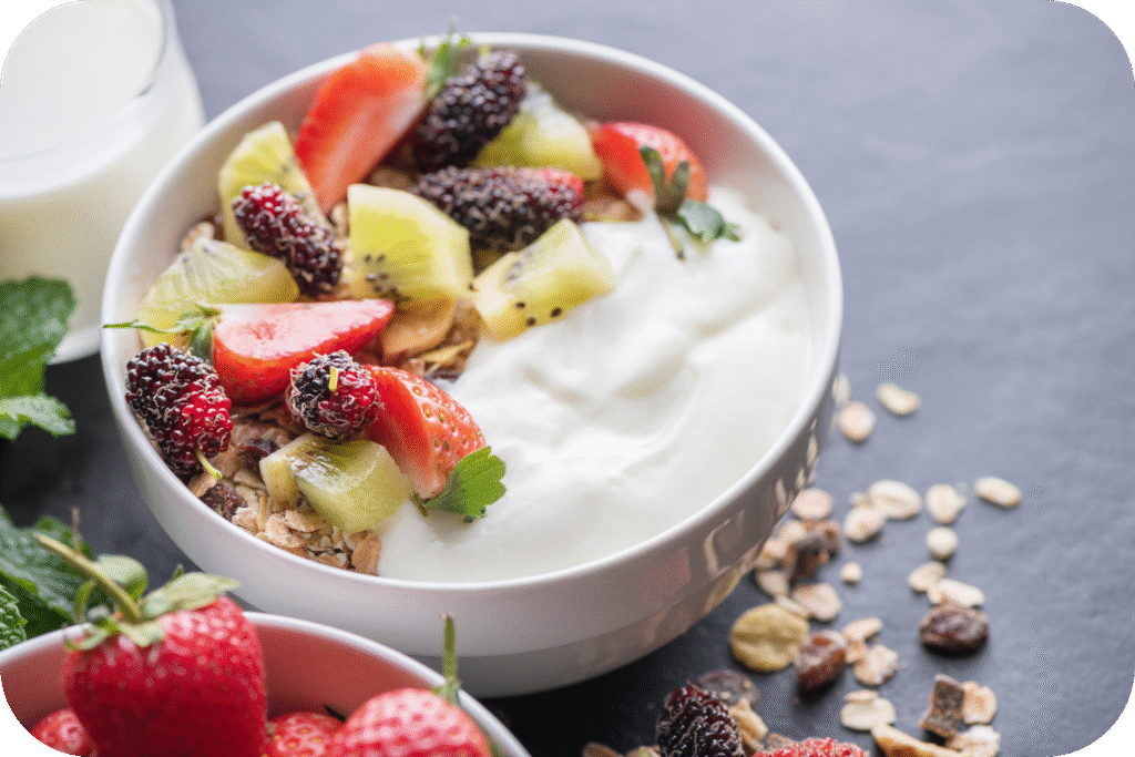 Sabores da primavera 3 tigela de granola de aveia com iogurte amora fresca morangos kiwi e nozes na placa de rocha preta para cafe da manha saudavel copie o espaco conceito de menu de pequeno almoco saudavel modified 1